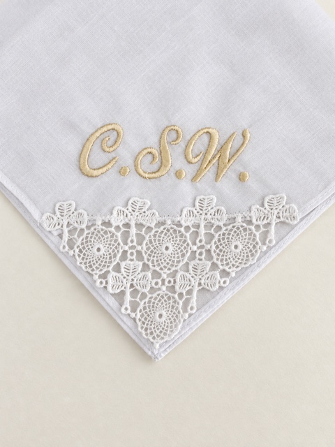 White handkerchief with a triangular floral lace insert and gold C.S.W. initials.