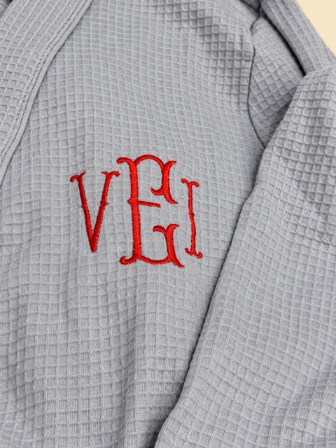 Gray waffle robe lapel and chest with an ornate three-letter red monogram.